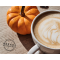 A steaming cup of coffee with latte art sits on a wooden table, with a mini pumpkin next to it, with a ‘Breaks Reimagined’ logo in the corner.
