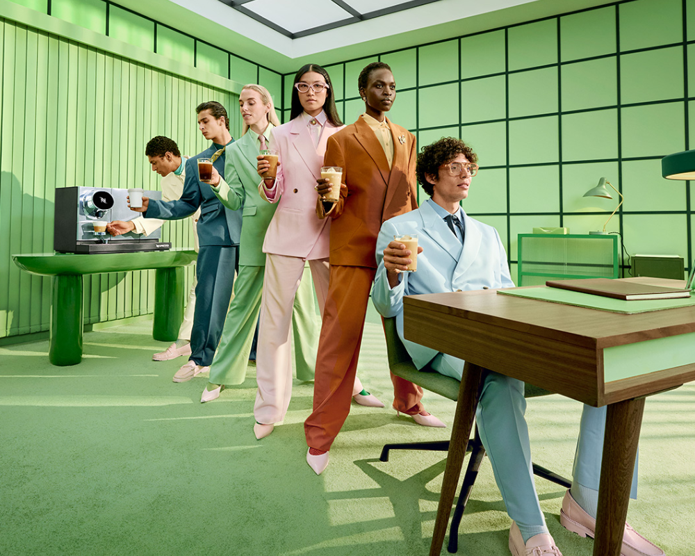 Six people in a line holding beverages made with the Nespresso Momento 100 machine.