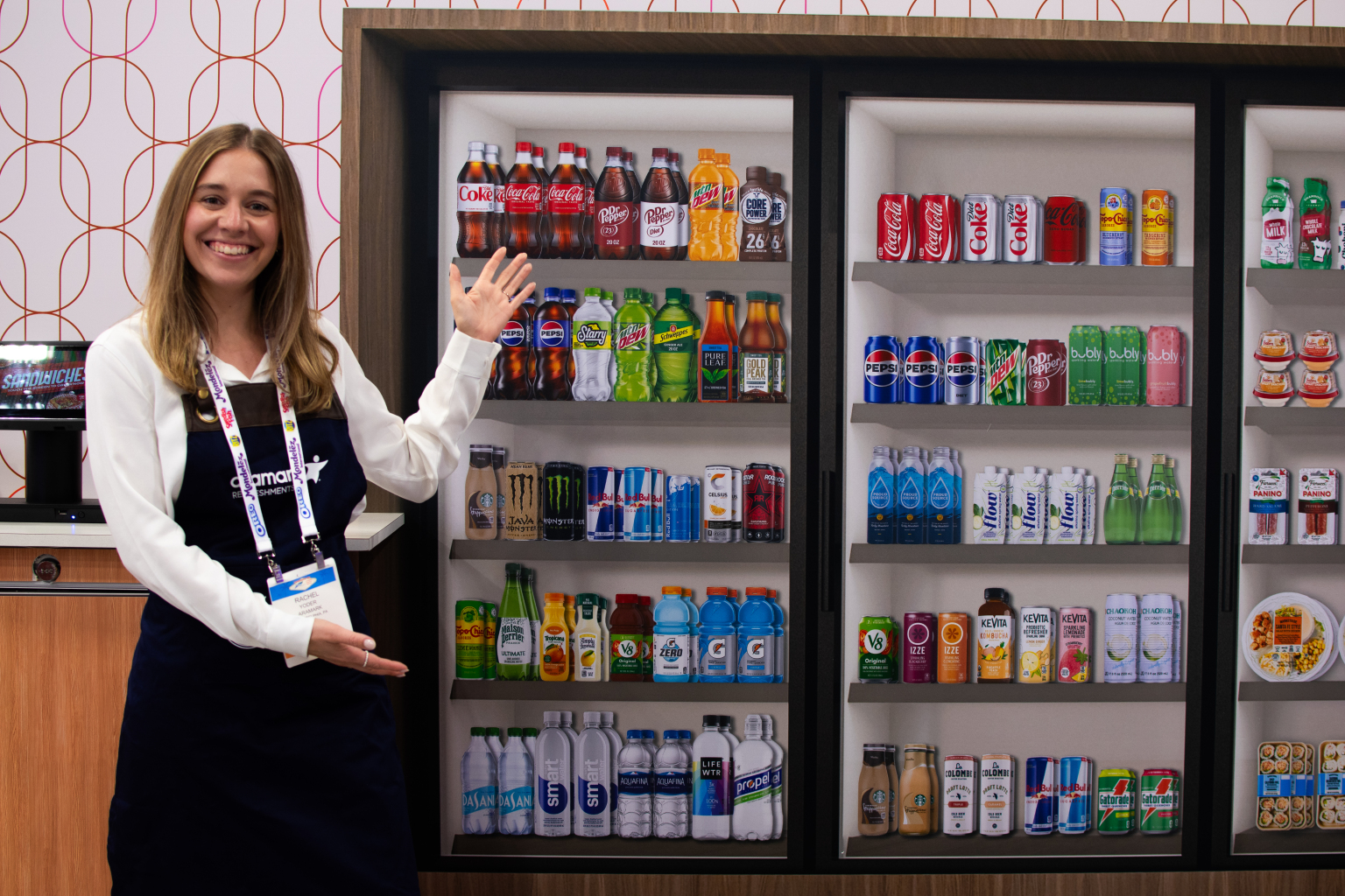 Smiling Aramark Refreshments employee standing in front of a vending display